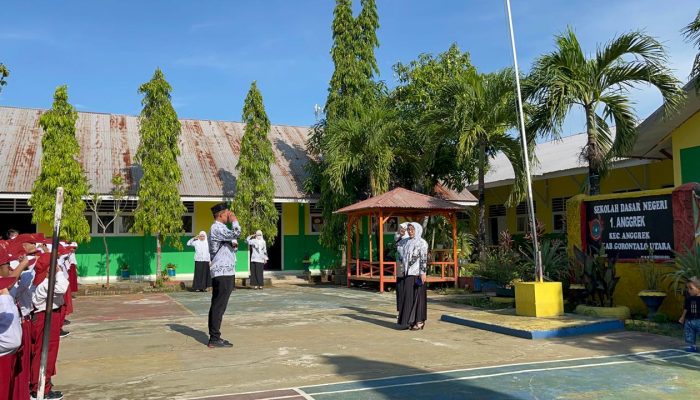 Para guru SDN 1 Anggrek mengenakan seragam PGRI saat melaksanakan upacara Hari Guru Nasional 2024 di lapangan sekolah. Mereka bertugas sebagai pengibar bendera, pembaca doa, serta pembina upacara. Kepala sekolah menyampaikan pidato tentang pentingnya peran guru dalam pendidikan.