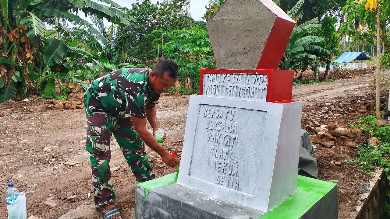Babinsa Kopda Jefri Samana dan Pratu Muhyidin tampak fokus mengecat tugu TMMD, bagian dari program pembangunan di Desa Ombulodata
