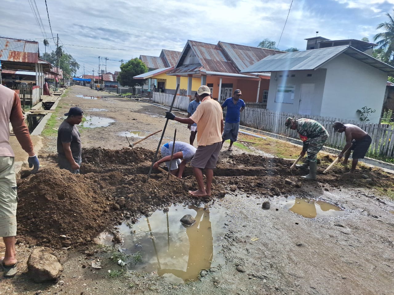 Sertu Parman  bersama warga tampak sibuk membersihkan tumpukan tanah yang menyumbat saluran air di kompleks pasar tradisional.